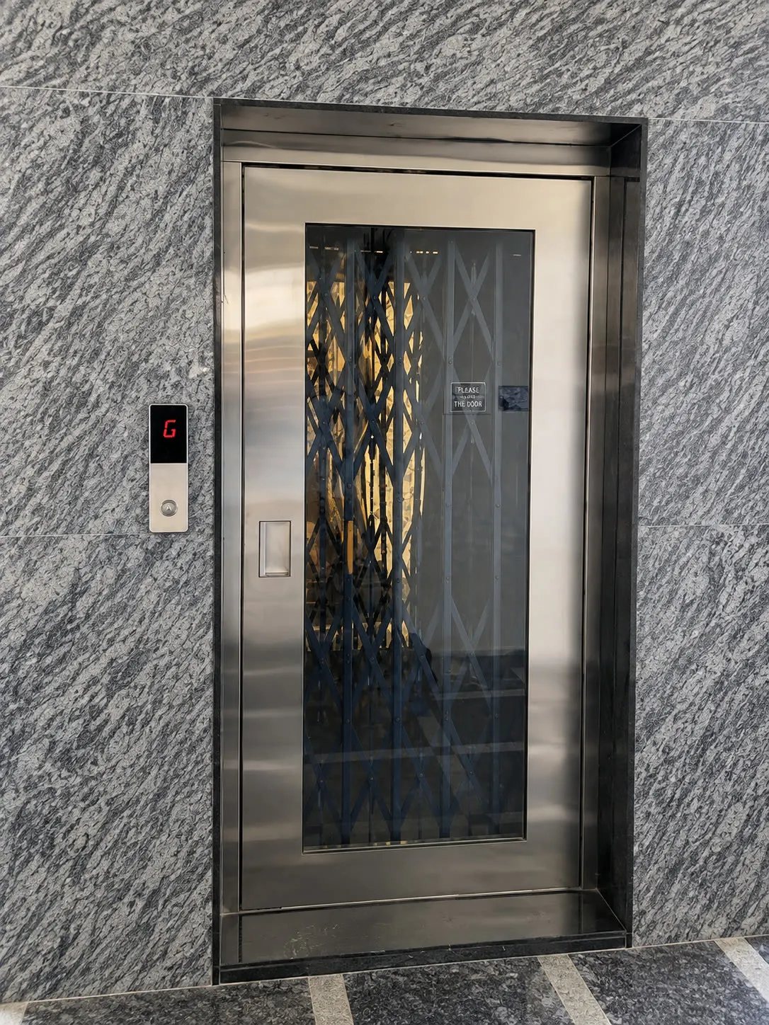 Home lift landing with stainless door in a granite surround
