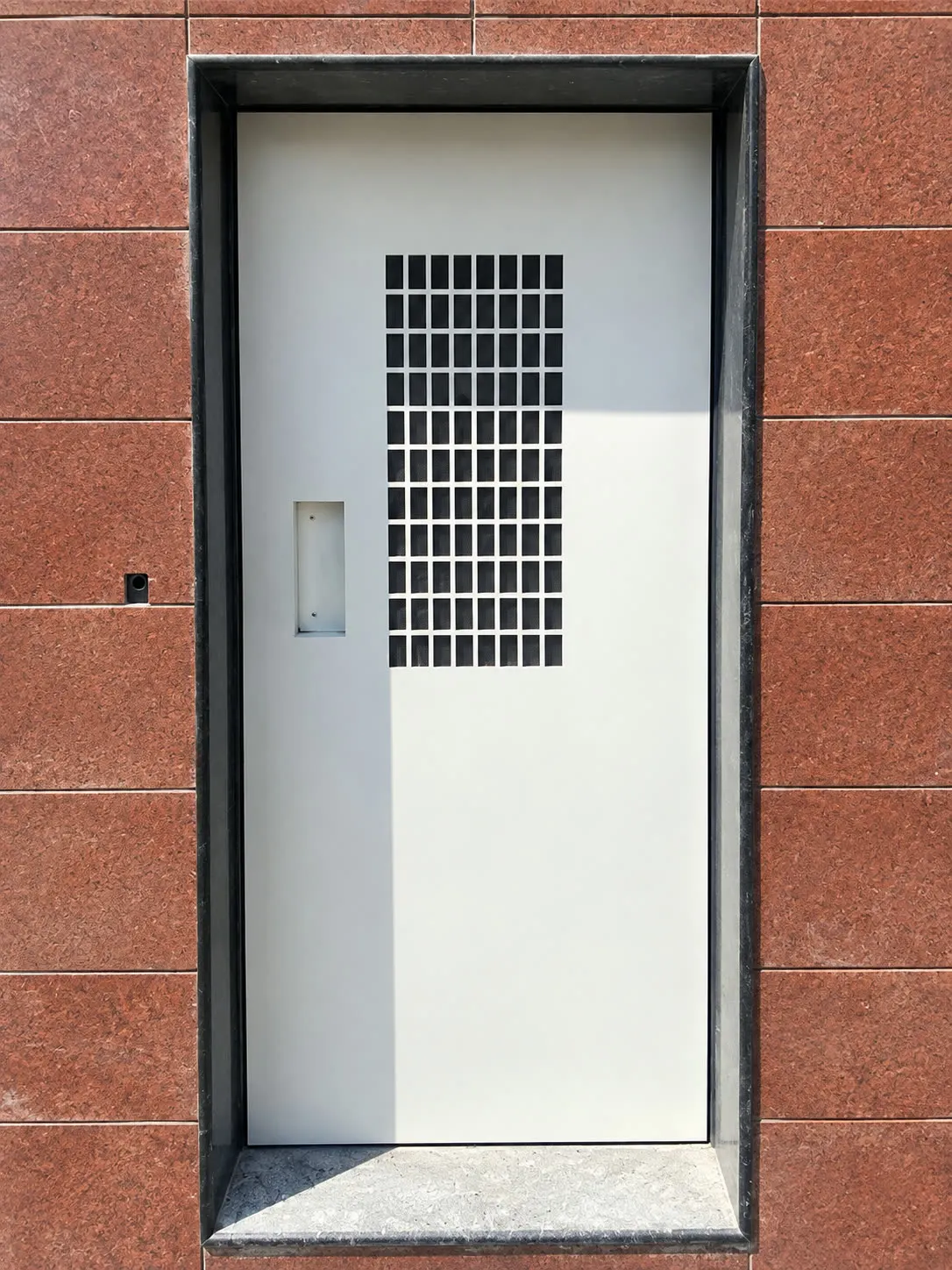 Home lift landing with a manual door in a tiled surround