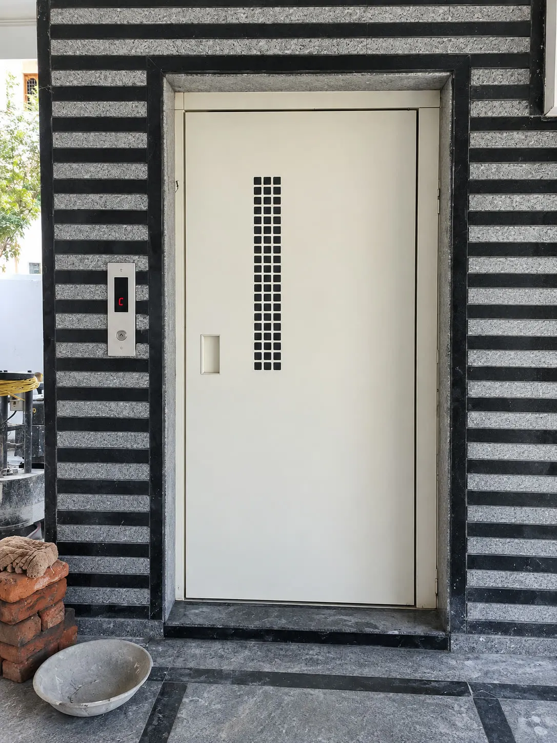 Home lift landing with a manual door in a granite surround