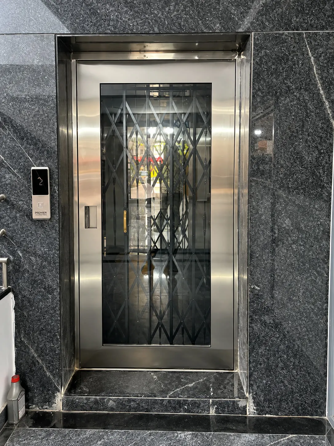 Home lift landing with a stainless door in black granite