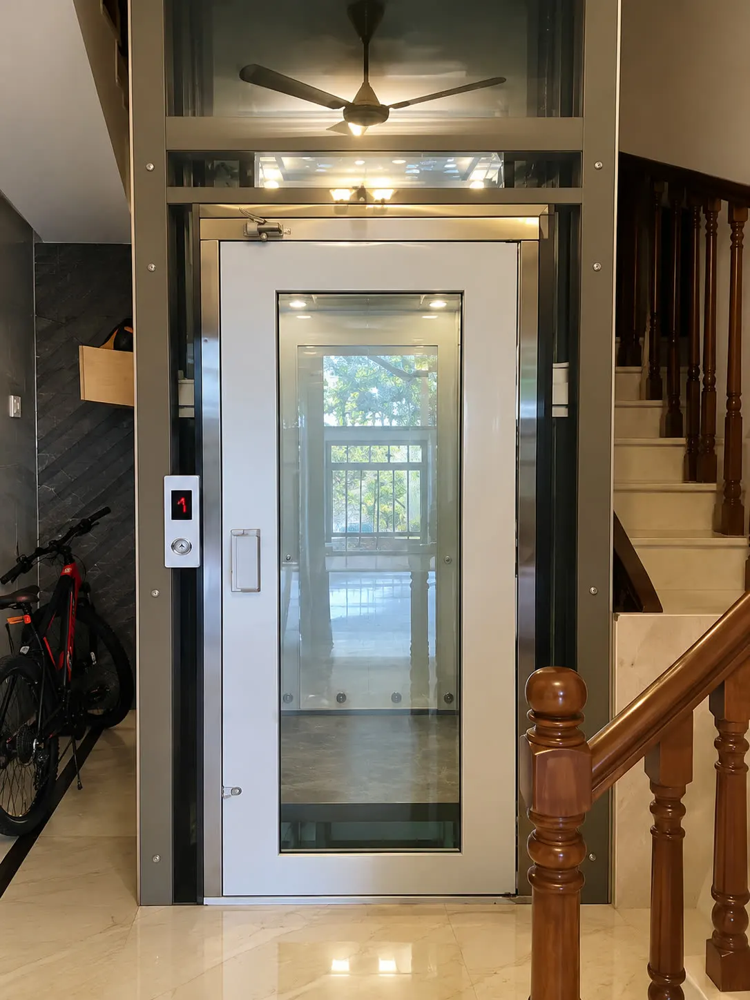 Glass-panel home lift door beside a staircase