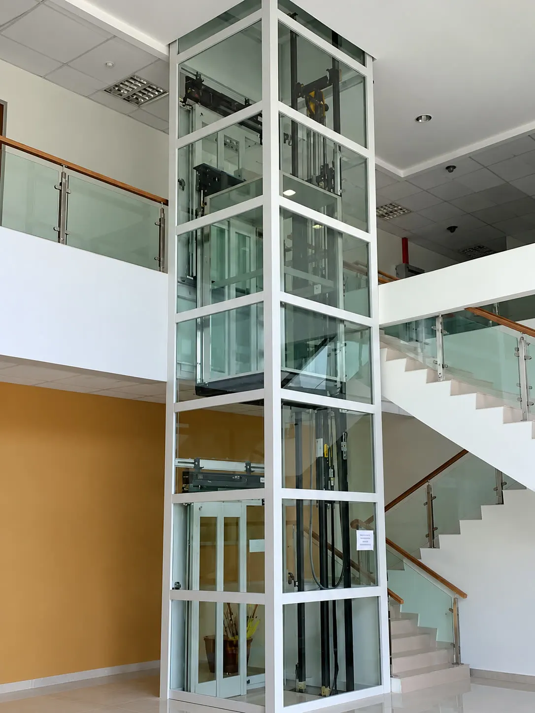 Full-height glass shaft home lift beside a staircase