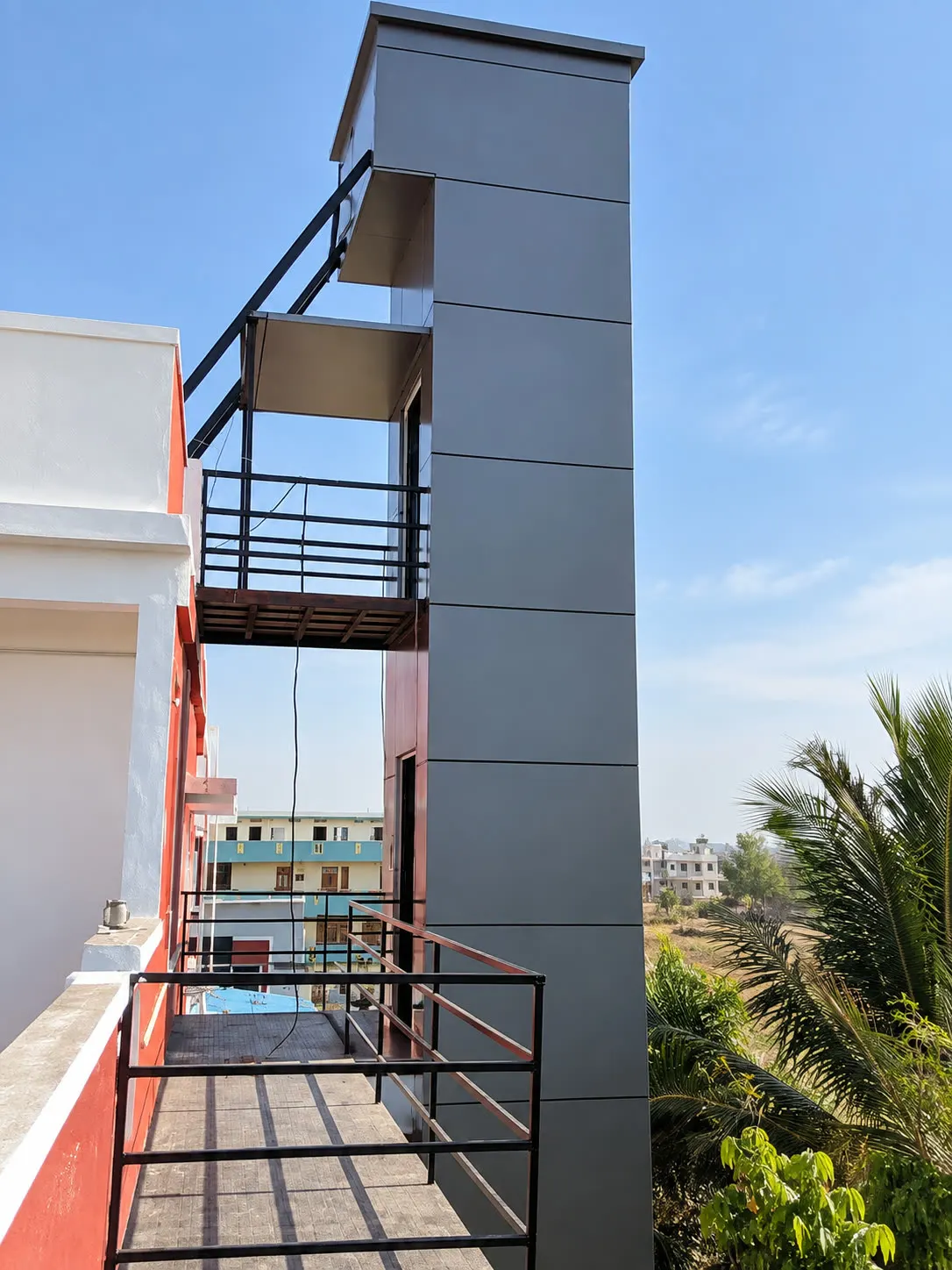Outdoor home lift shaft with metal cladding alongside a residence